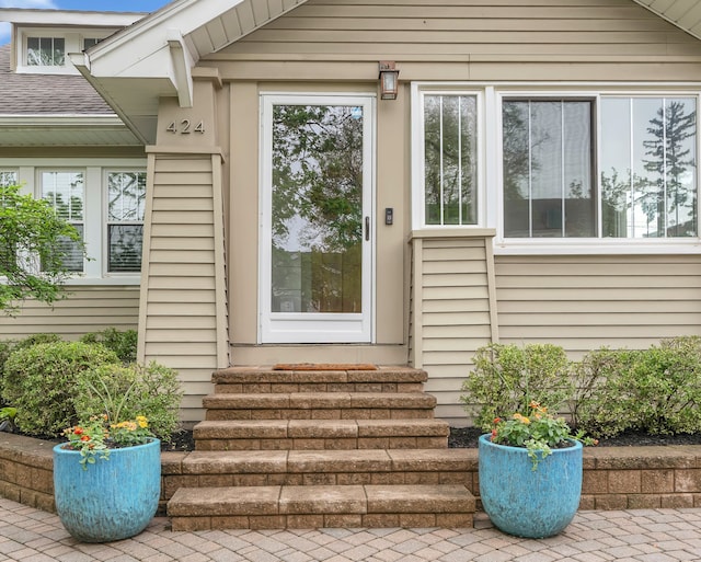 entrance to property featuring roof with shingles
