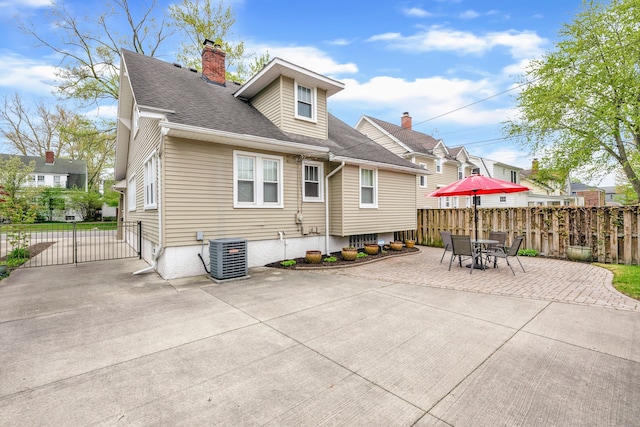 back of property featuring a patio, a chimney, fence, central air condition unit, and roof with shingles