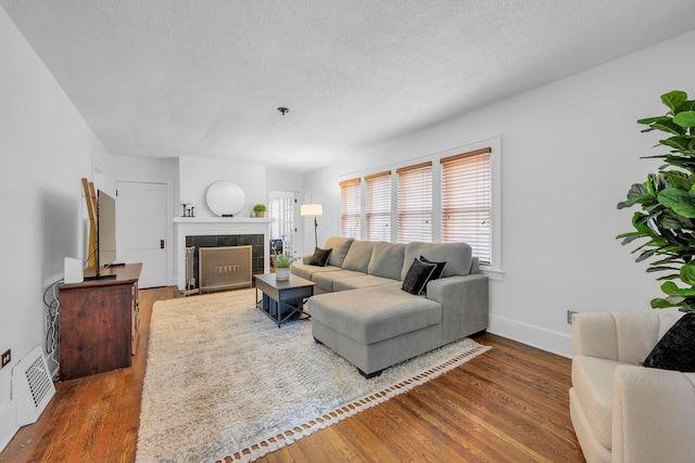 living area with a textured ceiling, visible vents, and wood finished floors