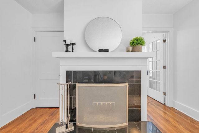 details with baseboards, a tiled fireplace, and wood finished floors