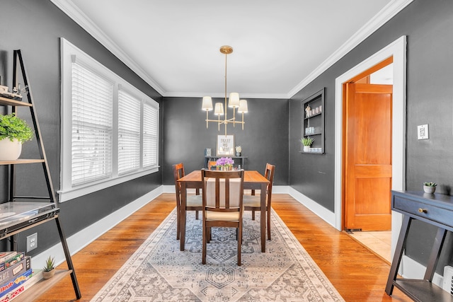 dining room with an inviting chandelier, ornamental molding, baseboards, and light wood-style flooring