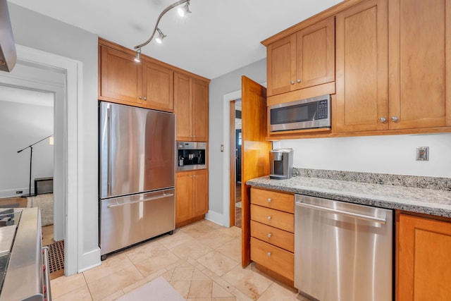 kitchen featuring brown cabinetry, stainless steel appliances, and light stone counters