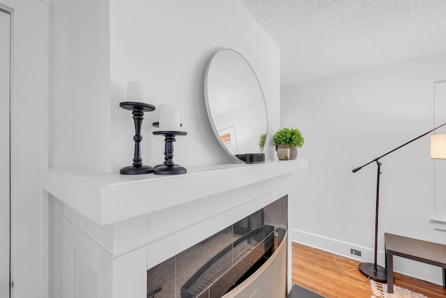 interior details with a textured ceiling, baseboards, and wood finished floors