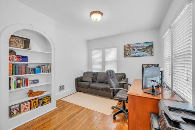 office area featuring baseboards, built in features, wood finished floors, and visible vents