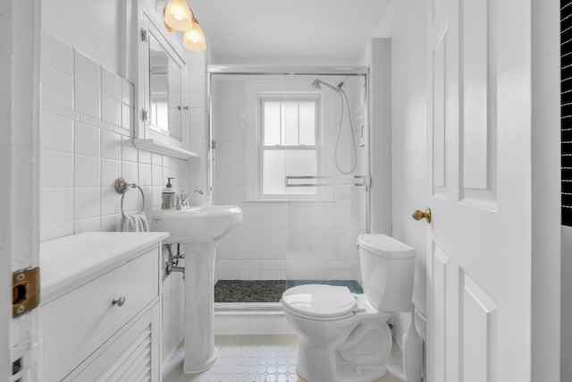 bathroom featuring a stall shower, tile patterned flooring, toilet, and a sink