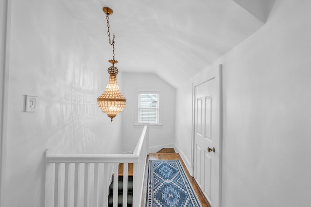 interior space featuring lofted ceiling, dark wood-style flooring, baseboards, and an upstairs landing