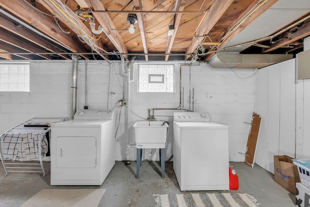 clothes washing area with washing machine and clothes dryer, a wealth of natural light, laundry area, and a sink