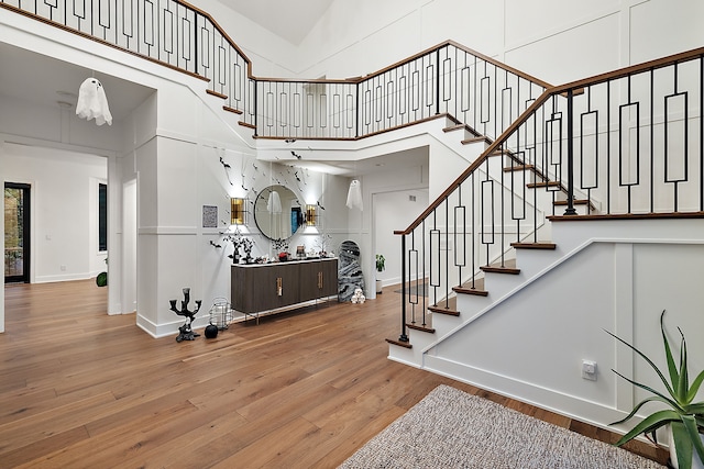 staircase featuring a high ceiling, baseboards, and wood finished floors