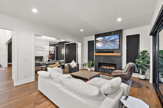 living room with light wood-style floors, a fireplace, baseboards, and recessed lighting