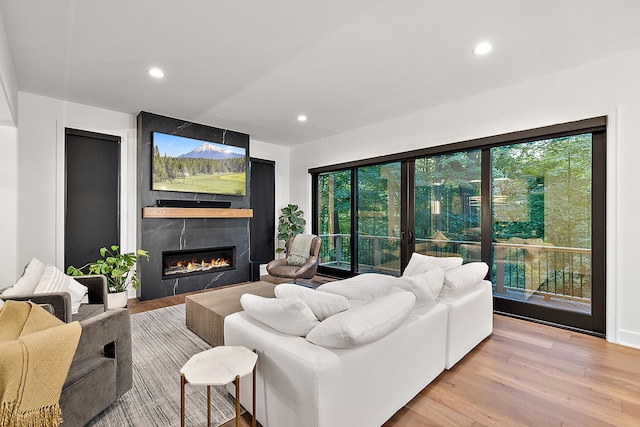 living room with a large fireplace, light wood-type flooring, and recessed lighting