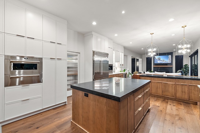 kitchen featuring a warming drawer, light wood finished floors, appliances with stainless steel finishes, and a center island