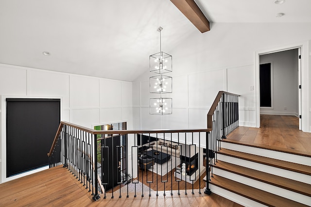 staircase with a decorative wall, a chandelier, vaulted ceiling with beams, and wood finished floors