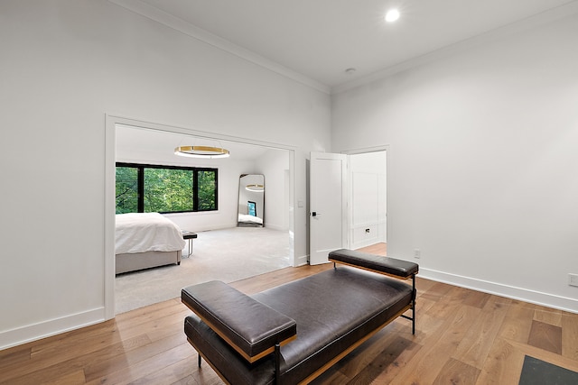 bedroom with ornamental molding, a high ceiling, baseboards, and wood finished floors