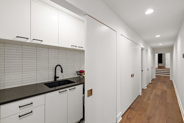kitchen with light wood-style flooring, a sink, dark countertops, decorative backsplash, and recessed lighting