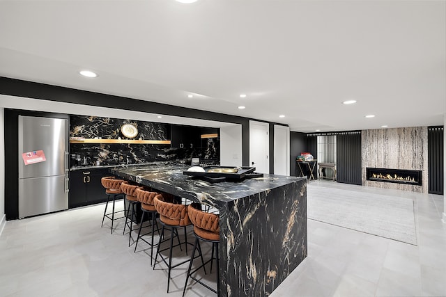 bar featuring a lit fireplace, freestanding refrigerator, wet bar, and recessed lighting
