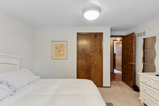 bedroom featuring a closet, visible vents, and light colored carpet