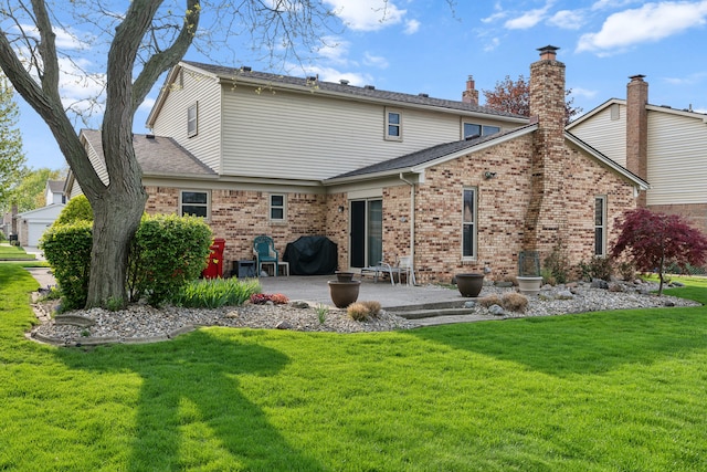 back of house featuring a yard, a patio, a chimney, and brick siding