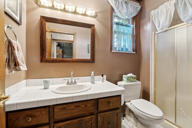 bathroom with a stall shower, vanity, and toilet