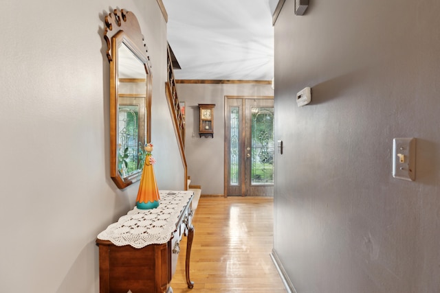 hall with baseboards, stairs, and light wood finished floors