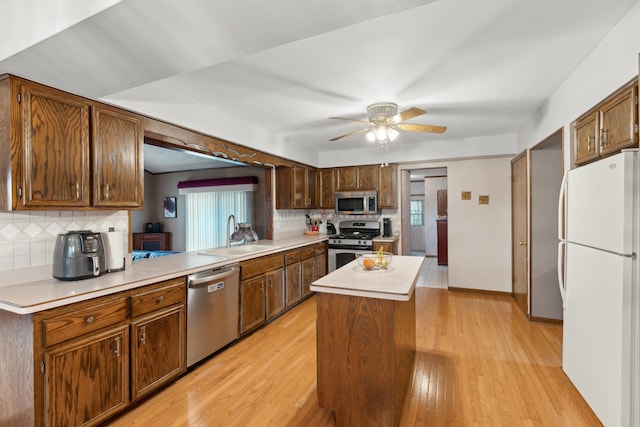 kitchen with a sink, stainless steel appliances, decorative backsplash, and a kitchen island