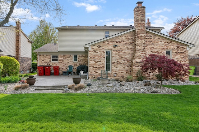 back of house featuring a lawn, a patio, and brick siding