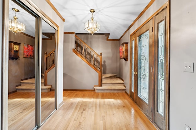 entrance foyer featuring stairs, a notable chandelier, baseboards, and light wood-style floors