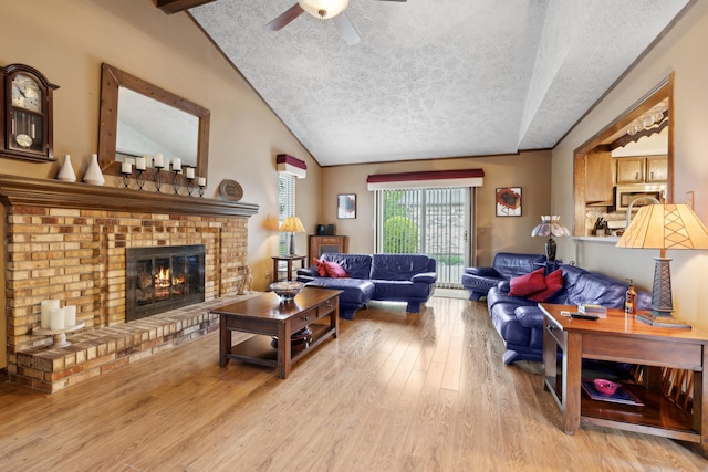 living room with a brick fireplace, a textured ceiling, wood finished floors, and vaulted ceiling with beams