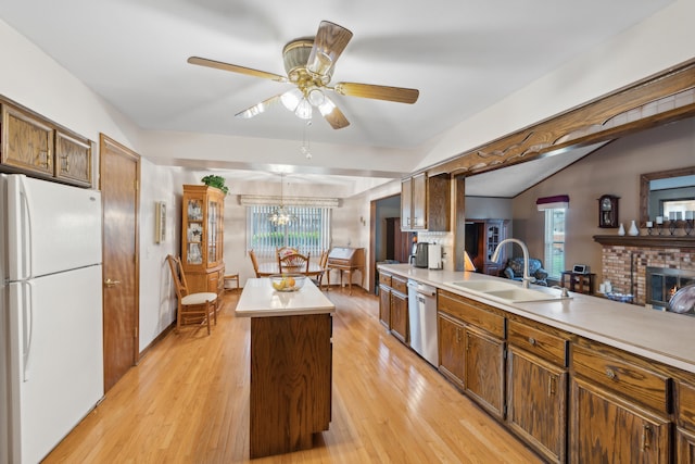 kitchen featuring freestanding refrigerator, dishwasher, a sink, a kitchen island, and light countertops