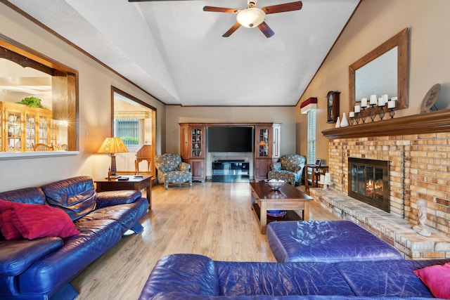 living area with a fireplace, wood finished floors, ceiling fan, and vaulted ceiling