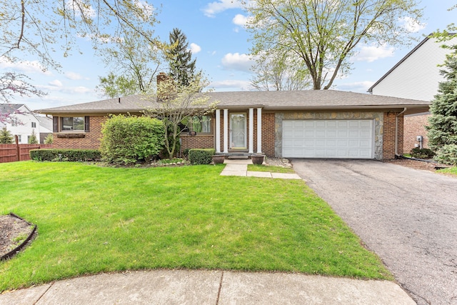 single story home featuring aphalt driveway, an attached garage, brick siding, and a front yard