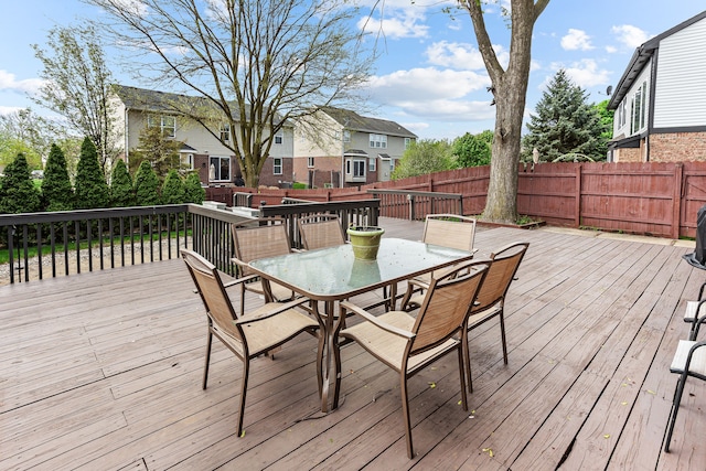 wooden terrace with outdoor dining space, a residential view, and fence