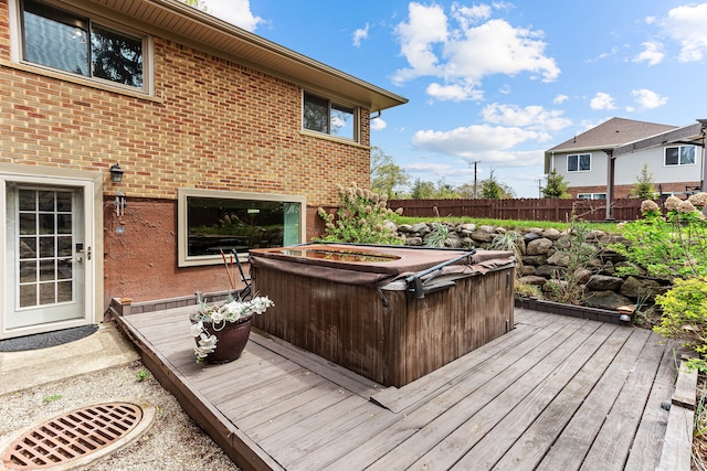 deck featuring a hot tub and fence