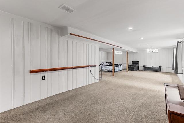 living area with recessed lighting, a decorative wall, visible vents, and carpet floors