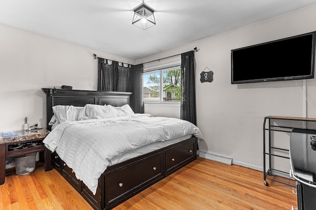 bedroom featuring light wood finished floors, baseboards, and baseboard heating
