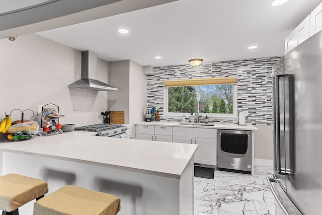 kitchen featuring freestanding refrigerator, wall chimney range hood, recessed lighting, and marble finish floor