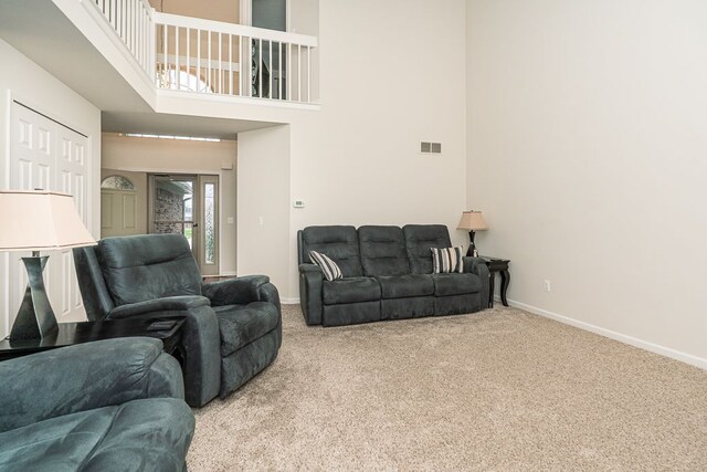 carpeted living room featuring baseboards and a towering ceiling