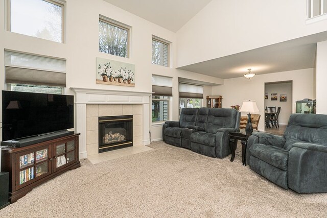 living room with high vaulted ceiling, light carpet, and a tile fireplace