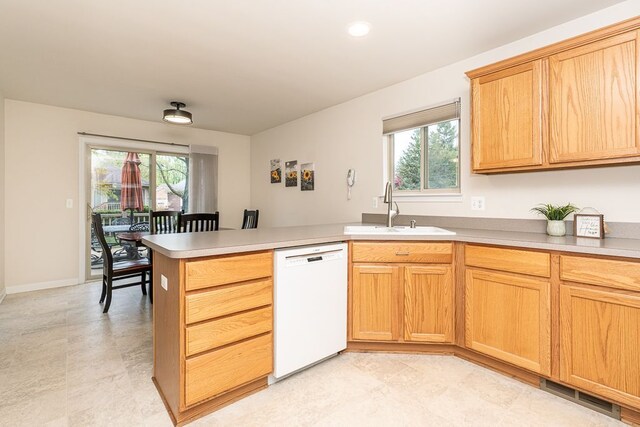 kitchen featuring dishwasher, a sink, a peninsula, and plenty of natural light
