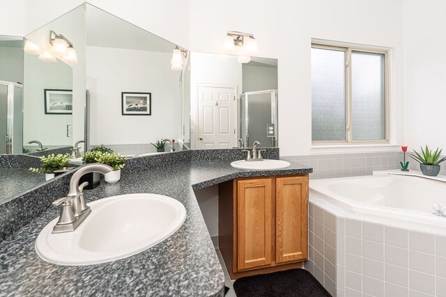 full bathroom featuring a stall shower, a bath, and double vanity