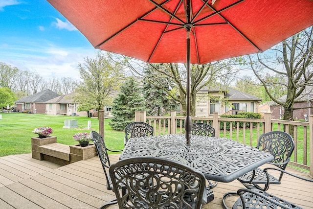 wooden deck featuring outdoor dining area, a yard, and a residential view