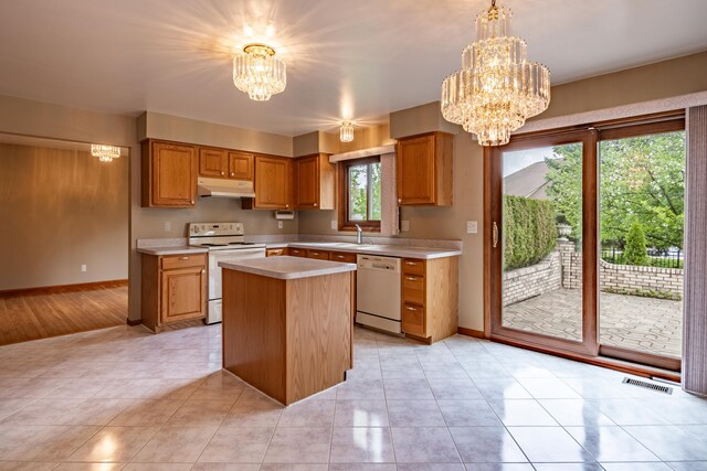 kitchen featuring white appliances, a chandelier, under cabinet range hood, light countertops, and baseboards