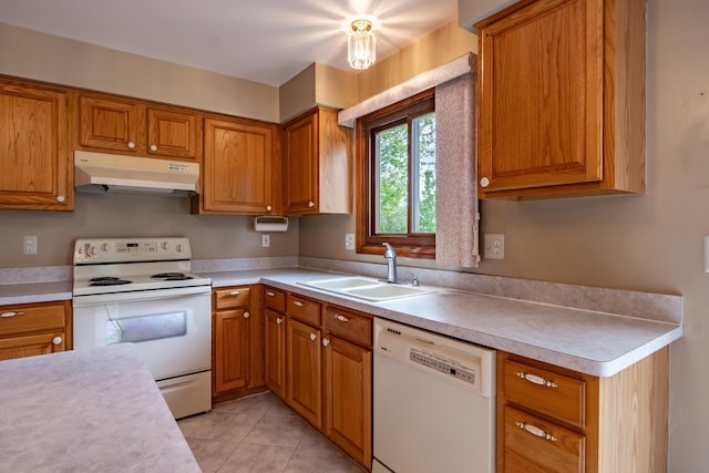 kitchen featuring white appliances, under cabinet range hood, a sink, light countertops, and brown cabinets
