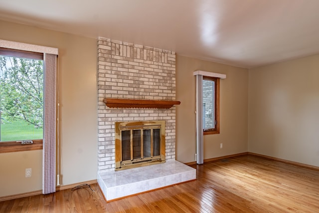 unfurnished living room featuring wood finished floors, a fireplace, and baseboards