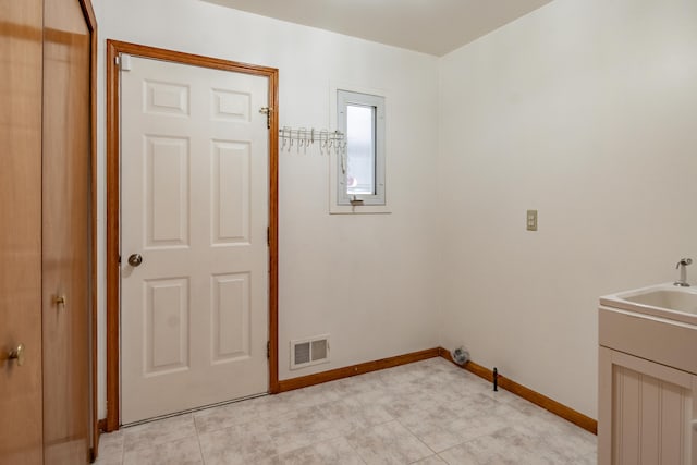 clothes washing area featuring baseboards and a sink