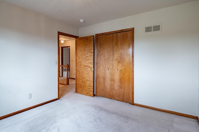 unfurnished bedroom featuring light carpet, a closet, and baseboards