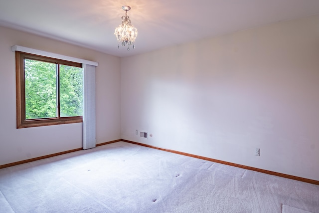 unfurnished room with a chandelier, baseboards, and light colored carpet