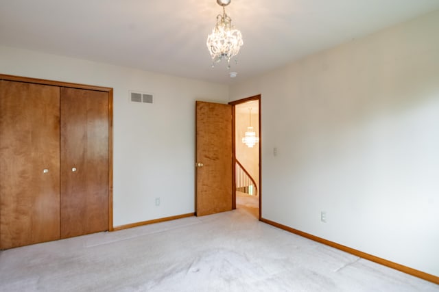 unfurnished bedroom with a chandelier, baseboards, light colored carpet, and a closet