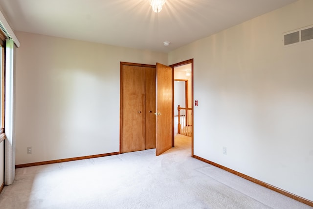 unfurnished bedroom with light colored carpet, baseboards, and a closet