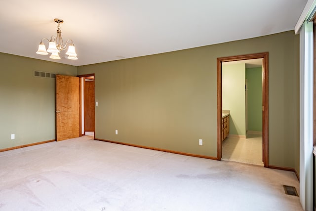 unfurnished bedroom with light colored carpet, a chandelier, baseboards, and connected bathroom