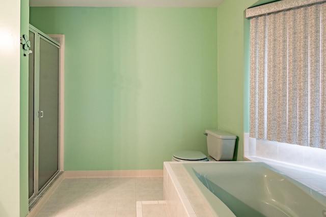 bathroom with tile patterned floors, a stall shower, a bath, toilet, and baseboards